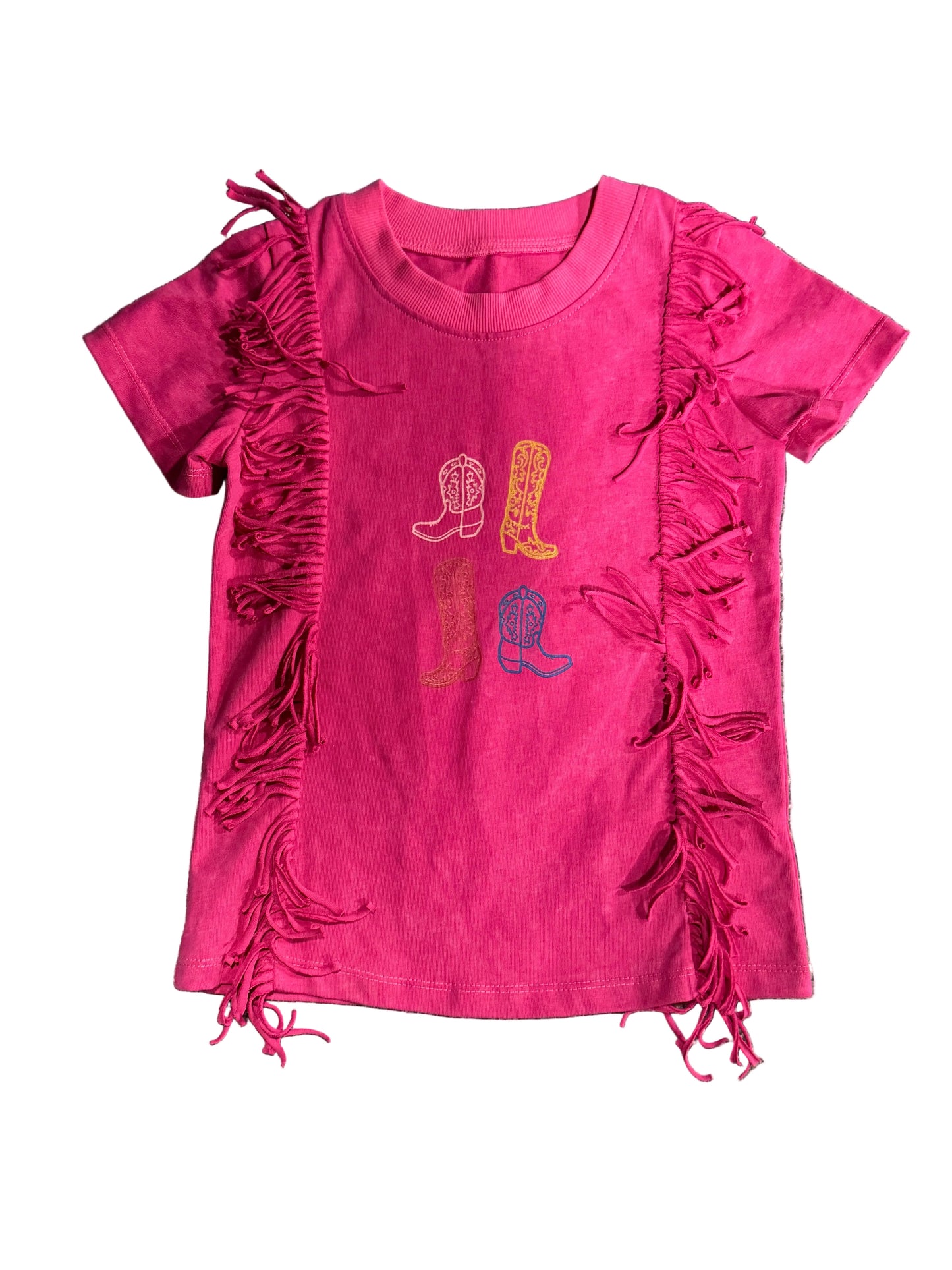 A bright pink short-sleeve t-shirt for kids, featuring fringe trim down the sides and a graphic of four cowboy boots in different colors on the chest, laid flat on a gray carpet.